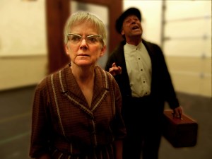 Woman in glasses with man signing behind her