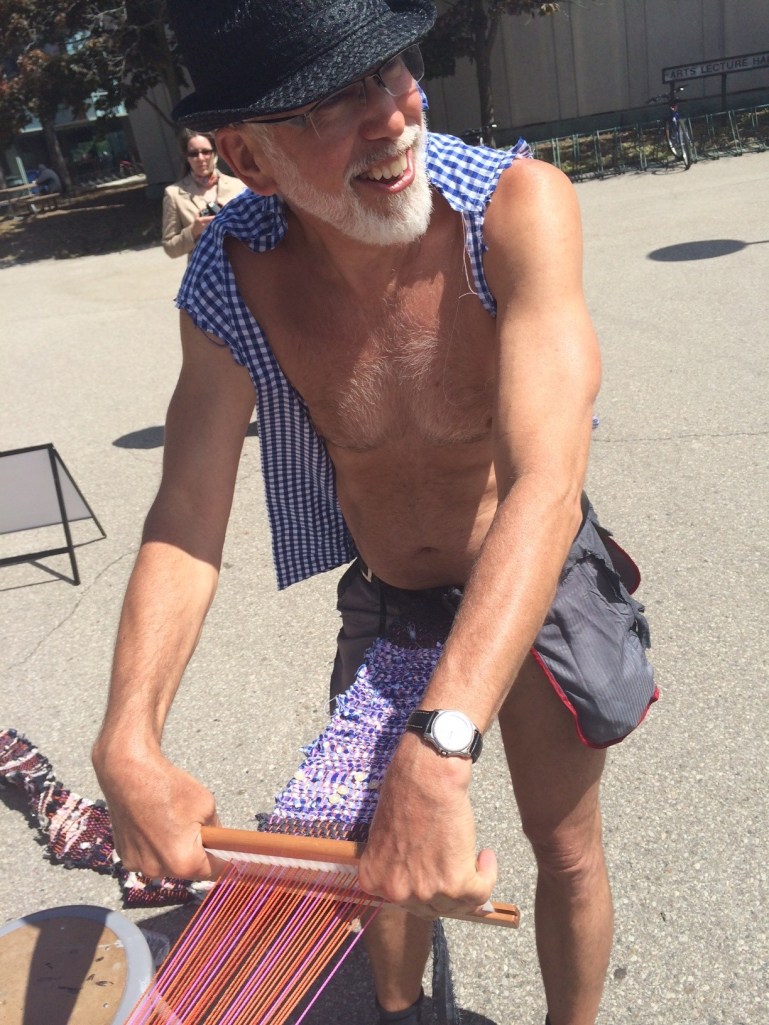 Barely dressed man weaving own clothes on loom