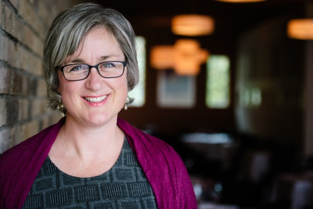 Woman smiling beside brick wall