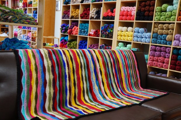 colourful yarn shop with leather couch and crocheted blanket