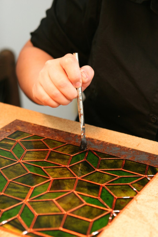 Woman holding brush working on stained glass project