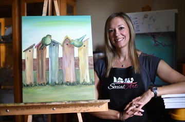 Woman standing beside painting on easel