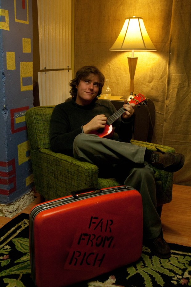 Man playing ukulele sitting in chair