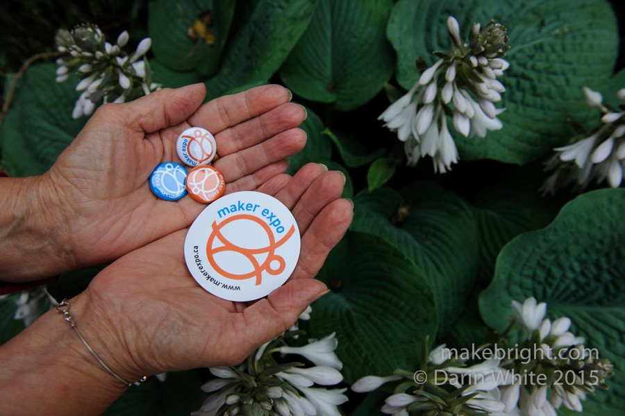 Hands holding maker expo buttons and stickers